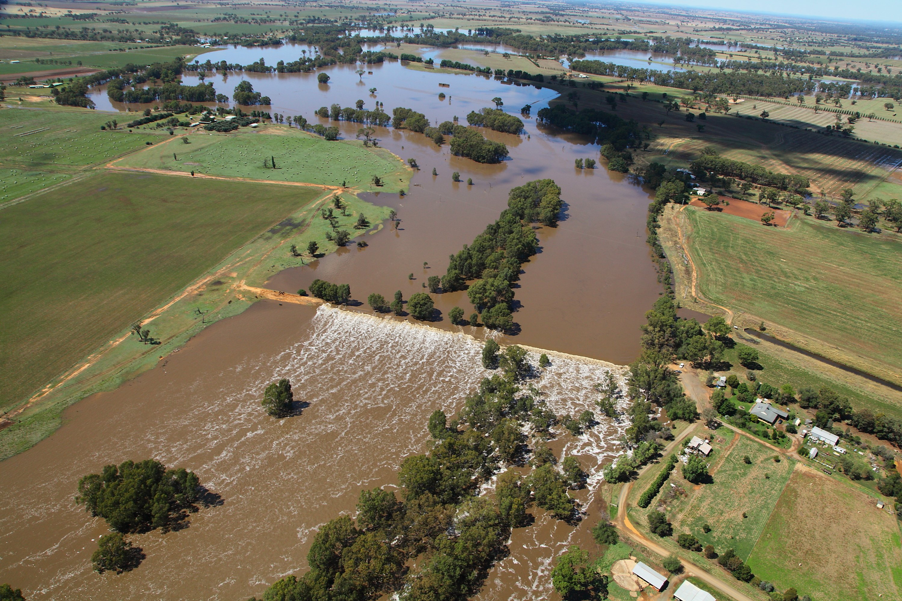 Image from the air of a weir in flood, surrounded by farmland.