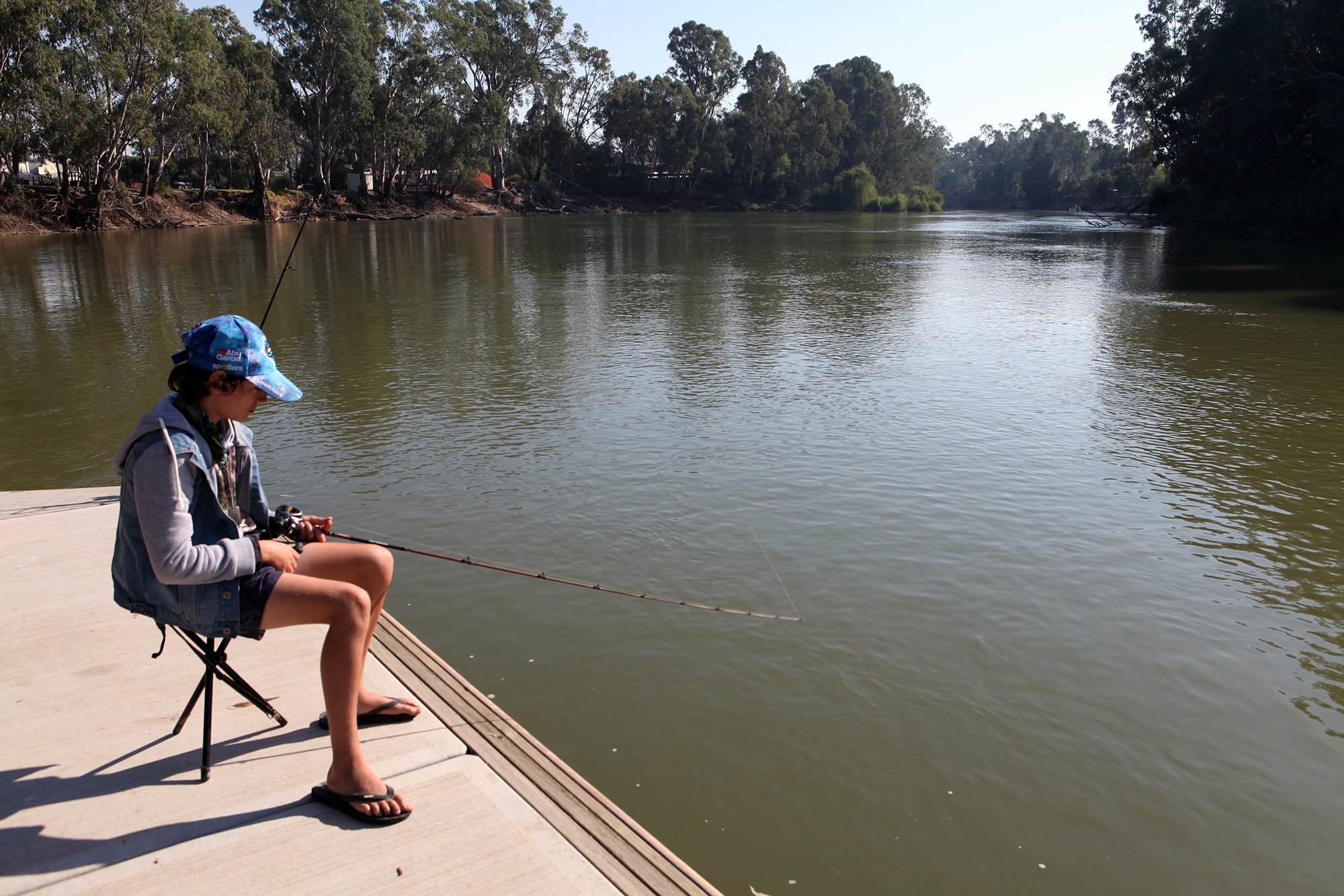 Boy sits on a platform fishing